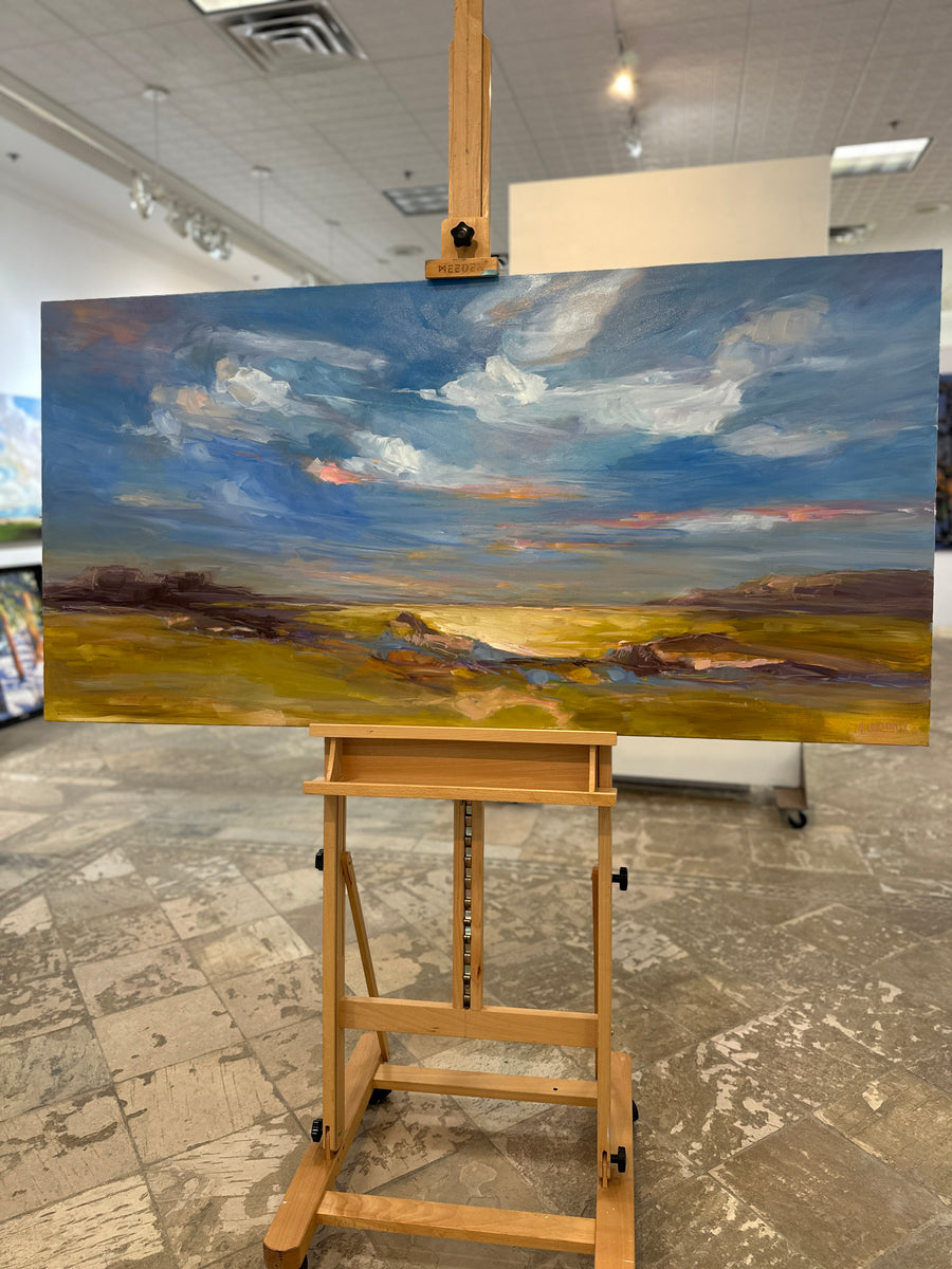 Wide landscape painting of clouds over golden fields, unframed, on an easel in Butter Gallery