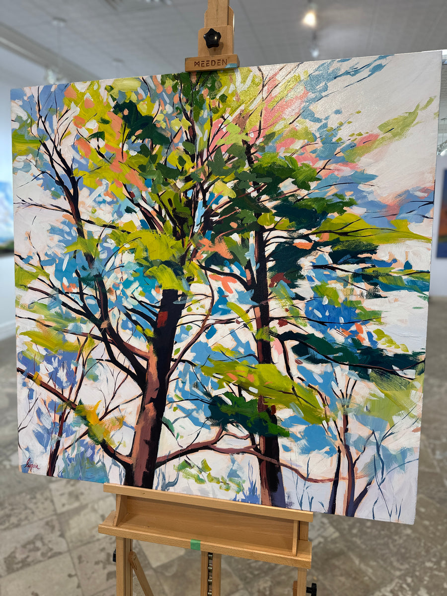 Painting of sunlit trees against a pale sky, unframed, on an easel in Butter Gallery