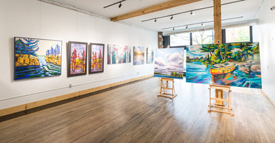 Inside Cloud Gallery in Orillia: paintings on white walls and easels on a wooden floor